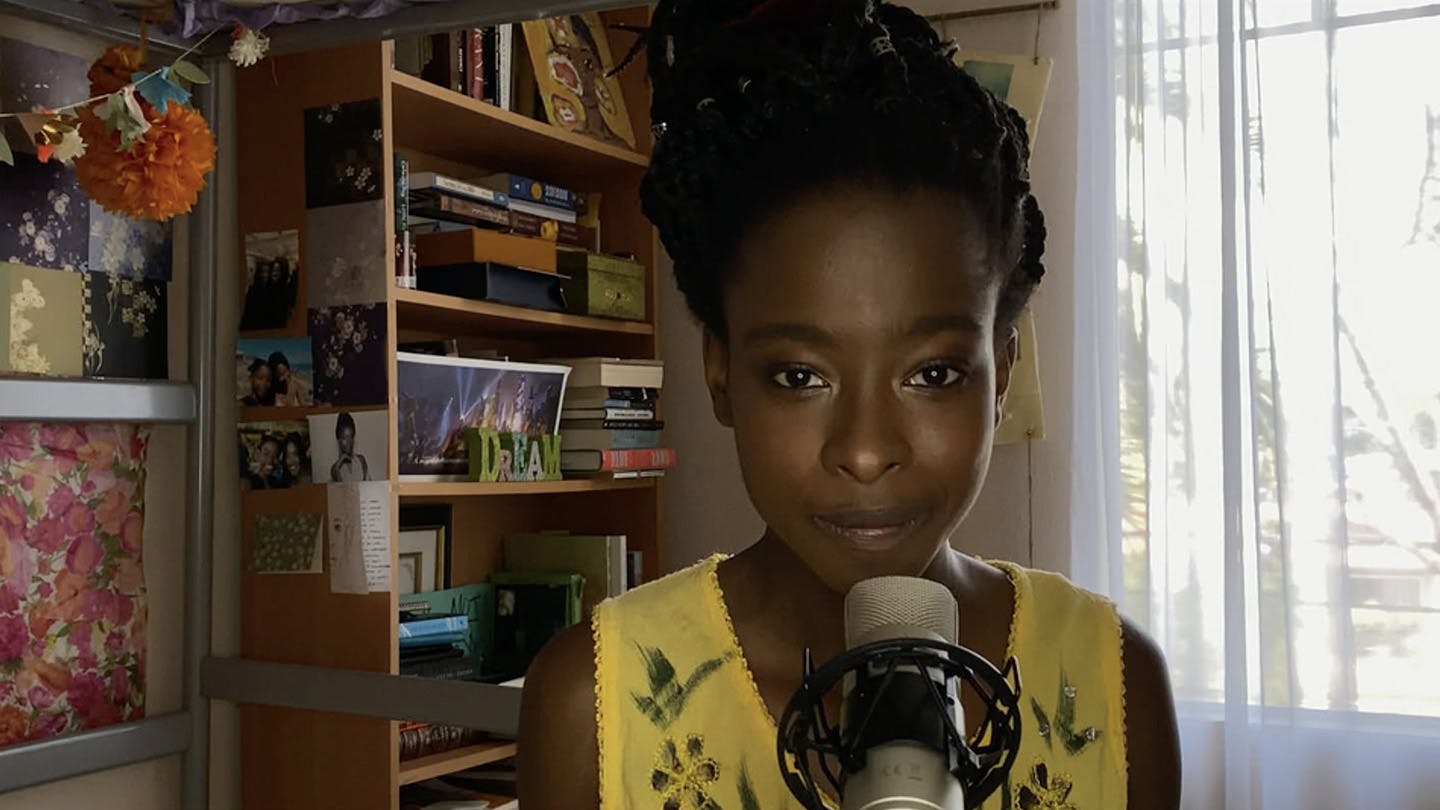 Close up of the youngest U.S. inaugural poet, Amanda Gorman, wearing yellow, leaning into the microphone in her room.