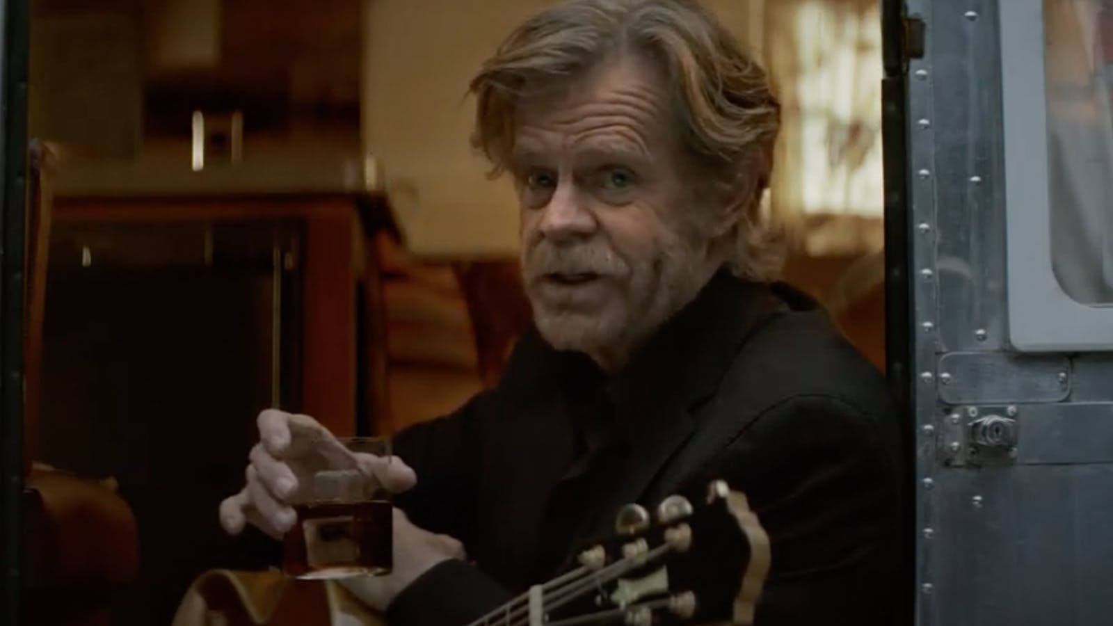 Screen grab of actor William H. Macy looking at the camera and raising a glass of bourbon for the Woody Creek campaign.