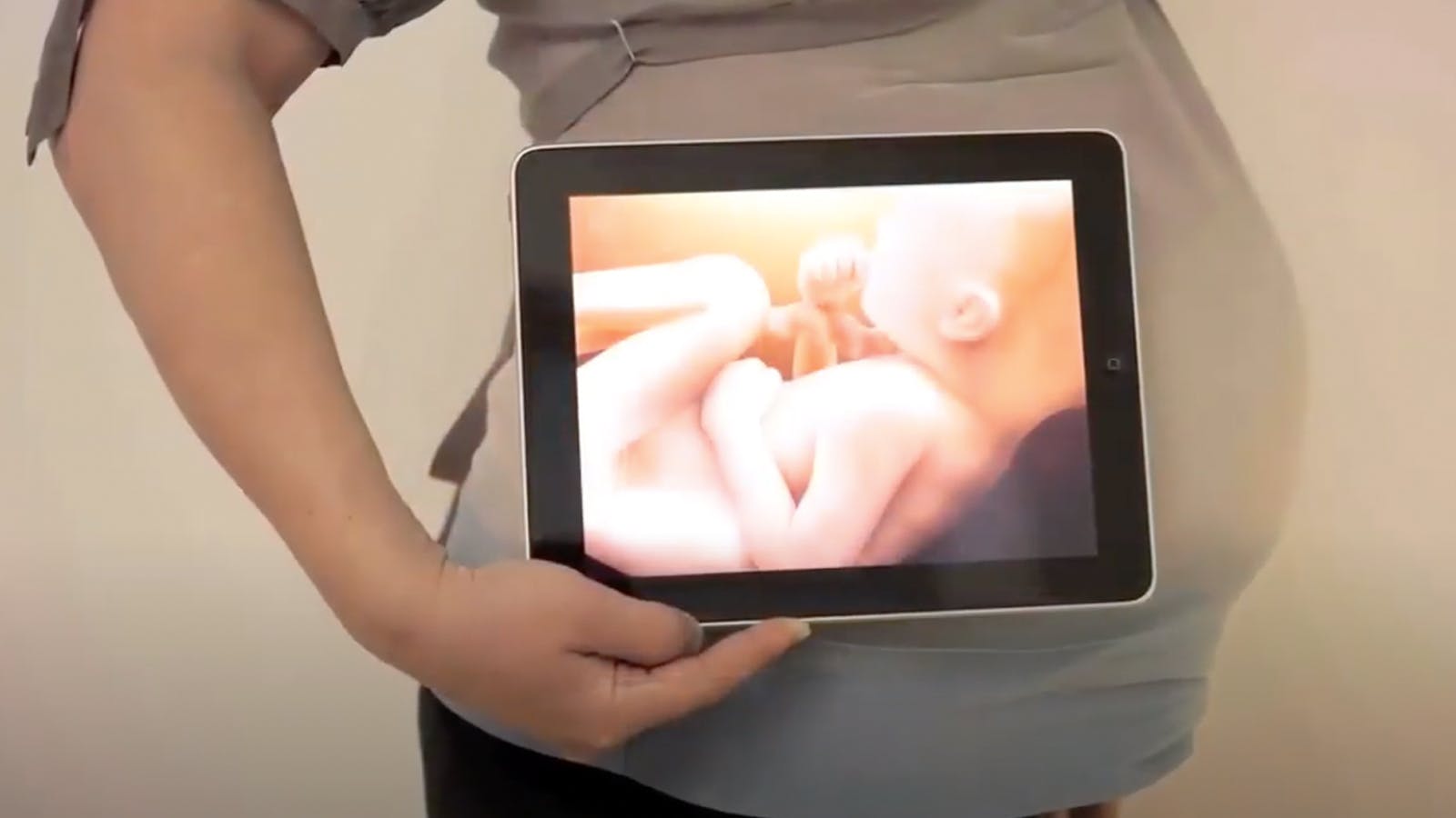 Pregnant woman holding a tablet that shows an image of the baby.