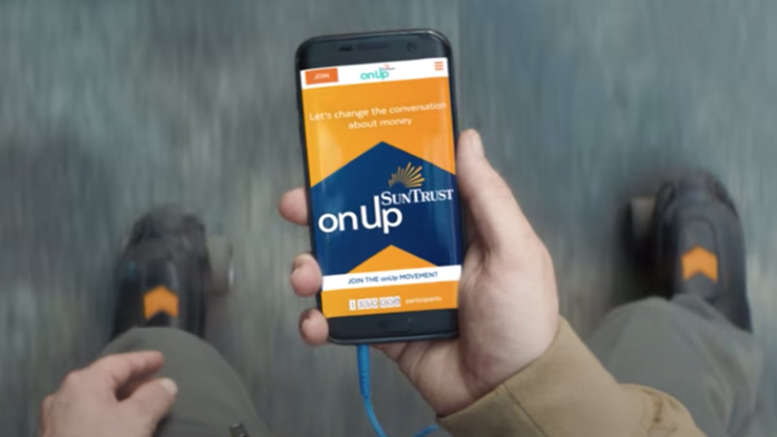 Point-of-view shot of a person holding a phone with the OnUp website on-screen. 