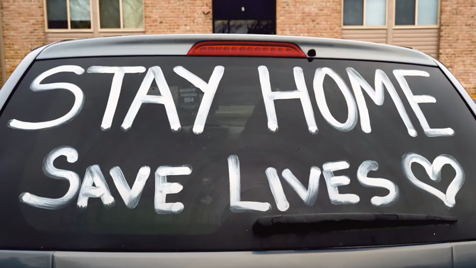 The text “Stay home, save lives” written on a windshield.